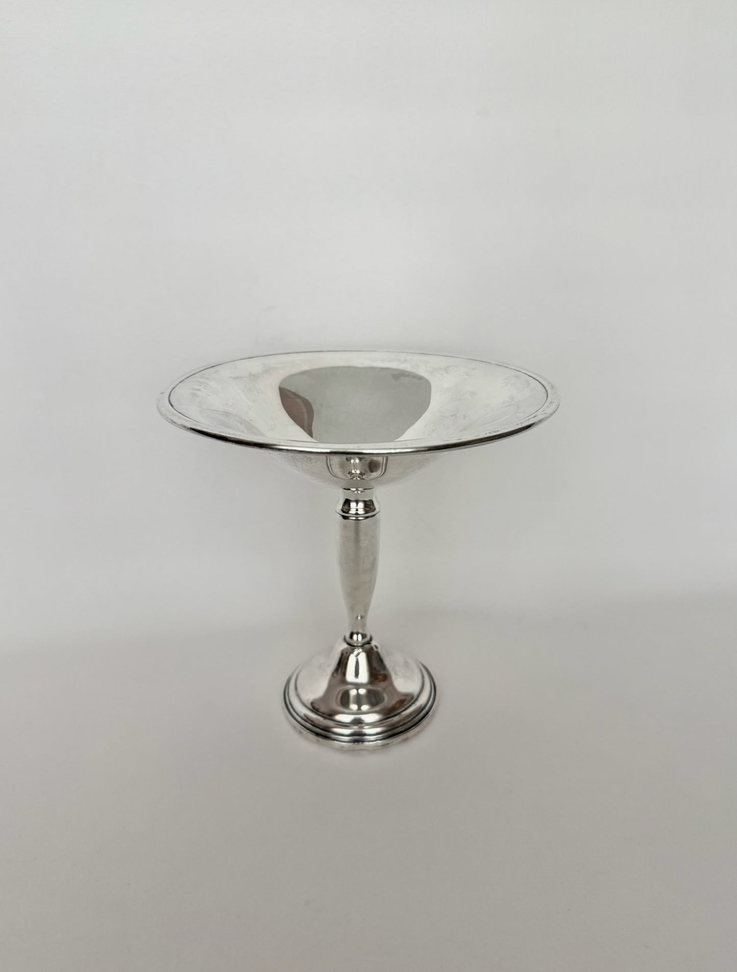 A polished vintage sterling silver pedestal dish with a wide, shallow circular bowl and a flared base