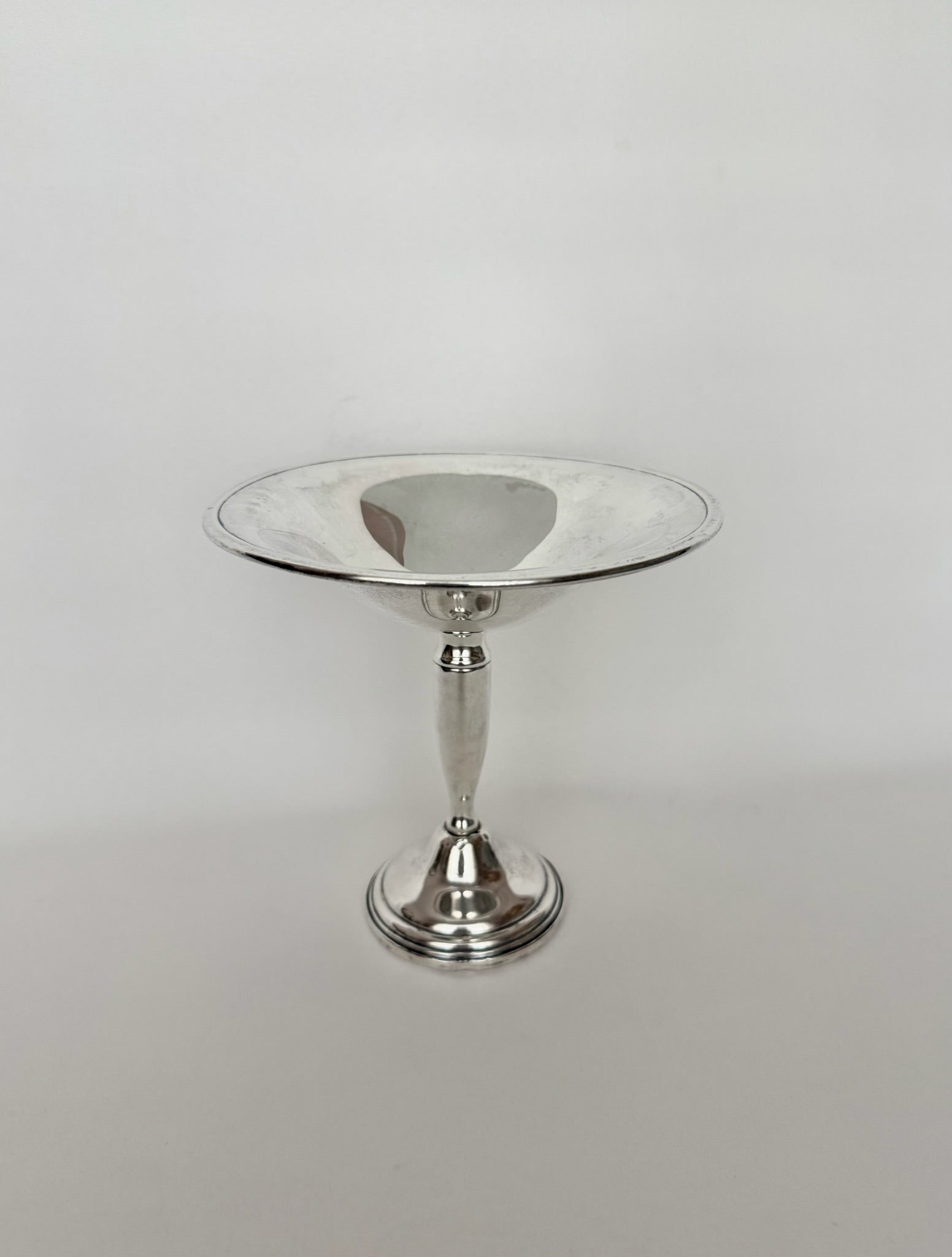 A polished vintage sterling silver pedestal dish with a wide, shallow circular bowl and a flared base