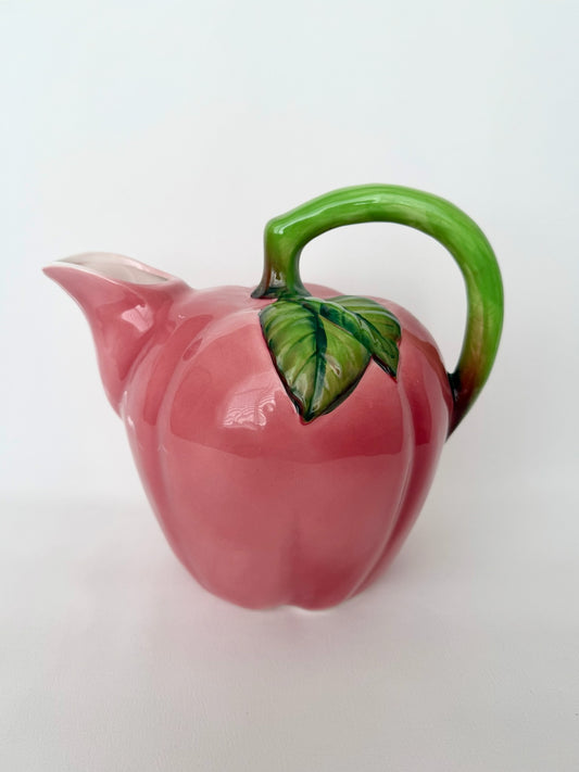 Vintage glazed ceramic apple pitcher with green handle detail.