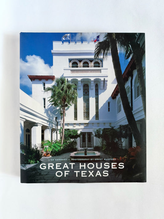 A hardcover book titled 'Great Houses of Texas' standing upright against a plain white background. The cover features a photograph of a white historic house with palm trees under a blue sky.