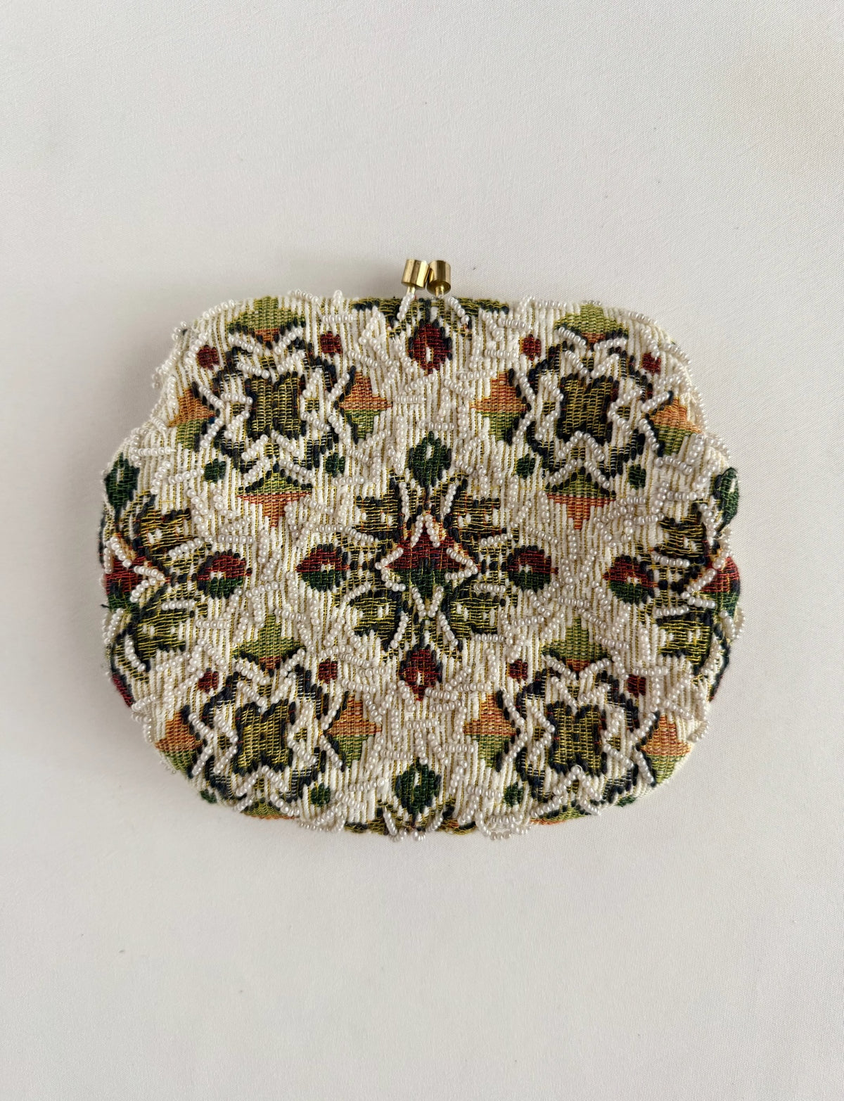 A vintage beaded clutch purse with an intricate floral pattern in green, red, and orange on a cream background, featuring a gold tones chain handle small gold-tone metal clasp at the top, 