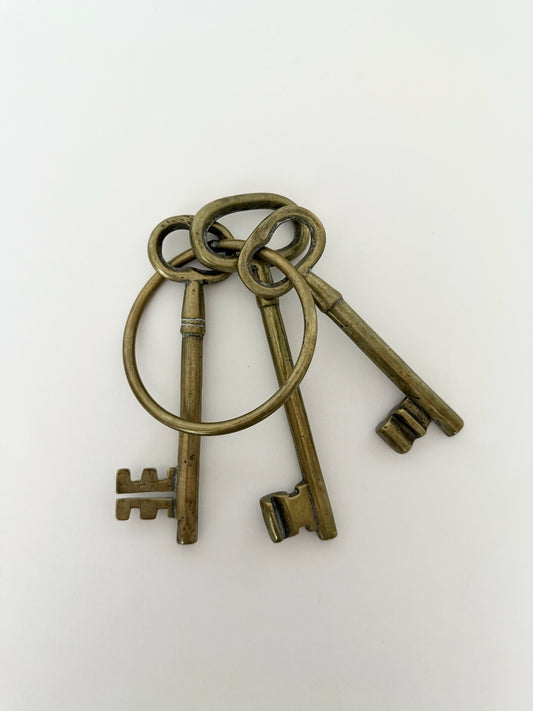 Vintage heavy brass skeleton keys on a large ring for decorative use.