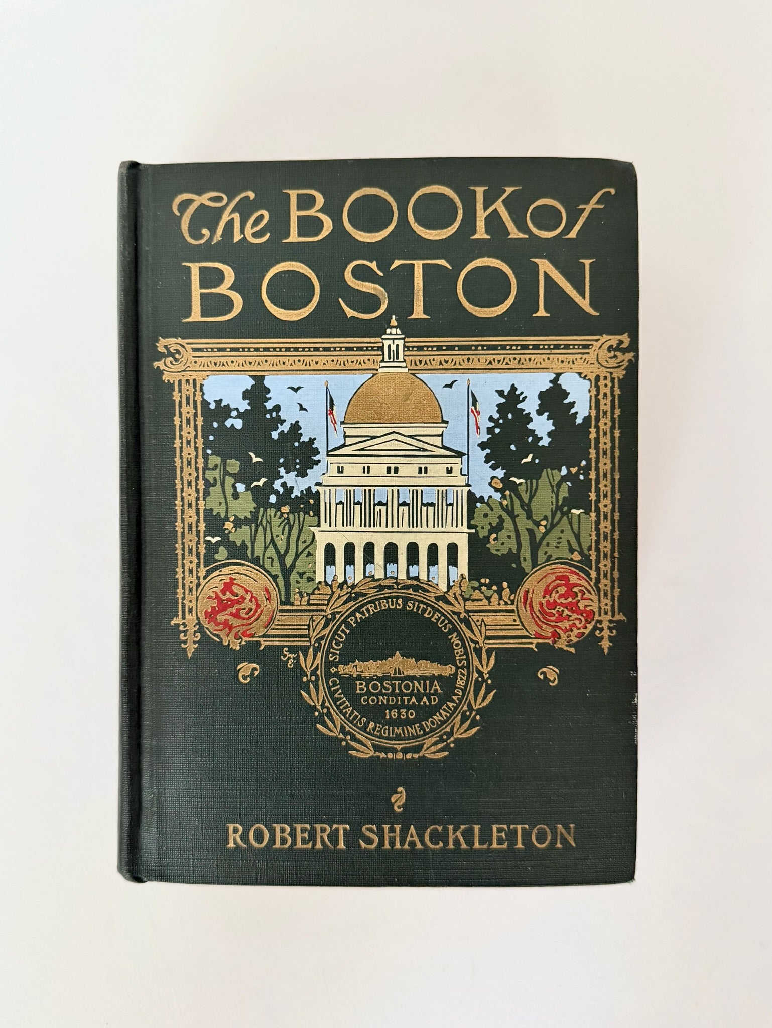 The Book of Boston by Robert Shackleton, featuring a dark green cloth-bound book cover with gold lettering and an illustration of the Boston State House. Antique book.