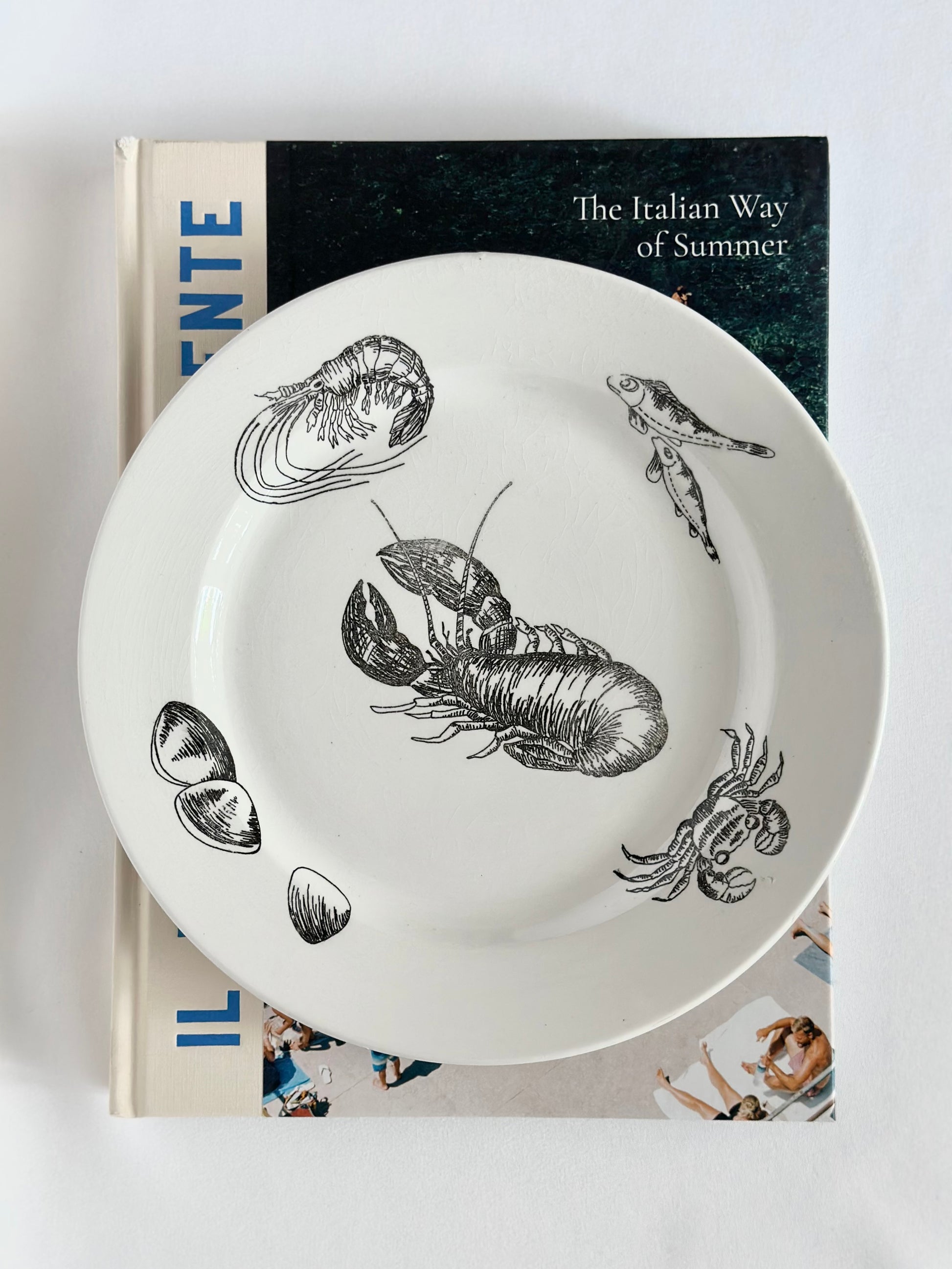 Vintage cream colored ceramic plates with black illustrated fish and shellfish