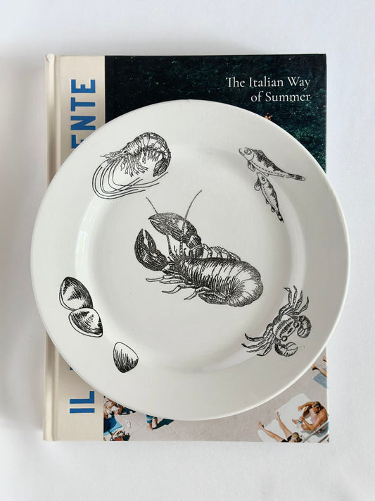 Vintage cream colored ceramic plates with black illustrated fish and shellfish