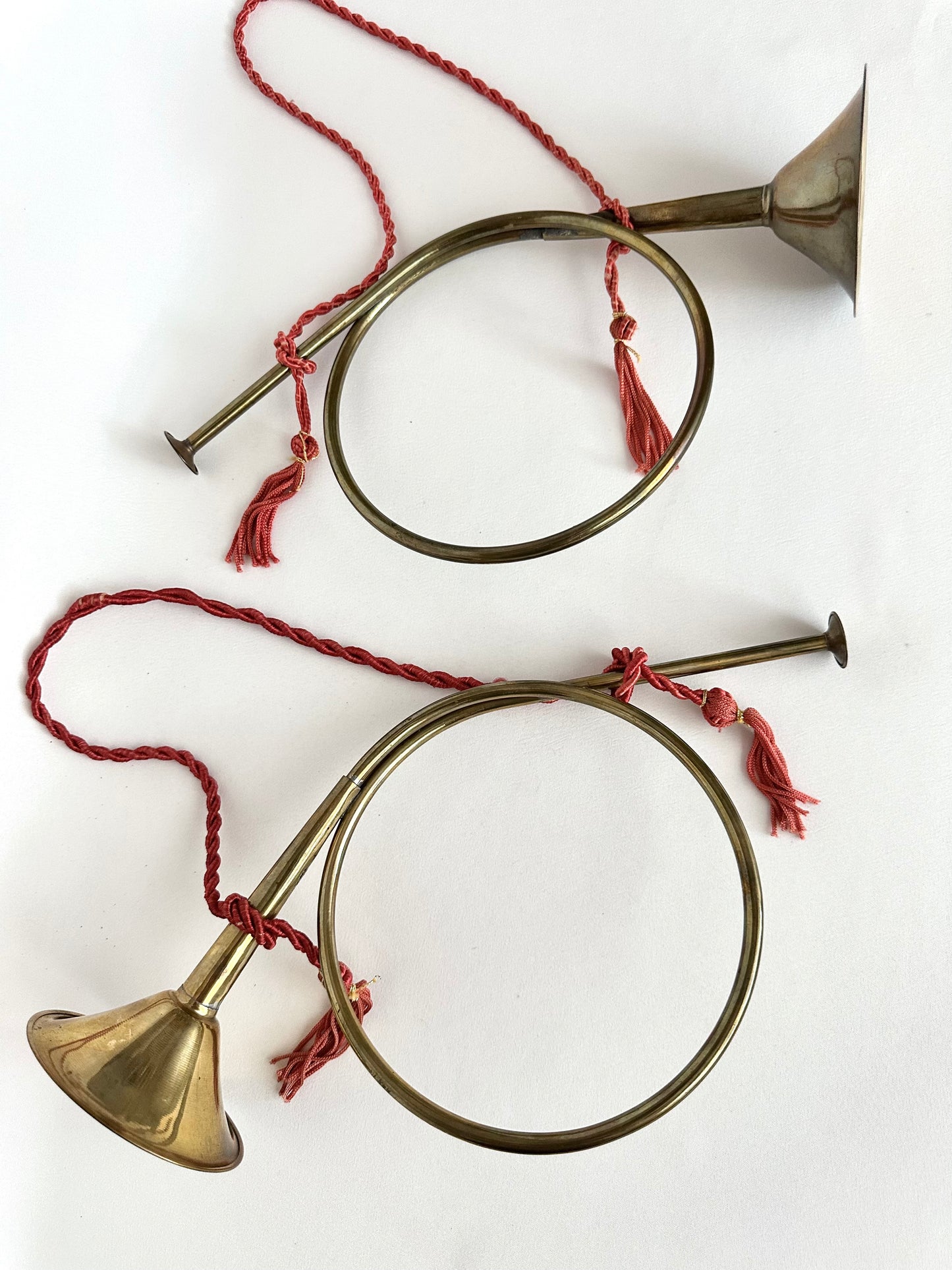Vintage brass French horn set of two on braided red rope tassels.