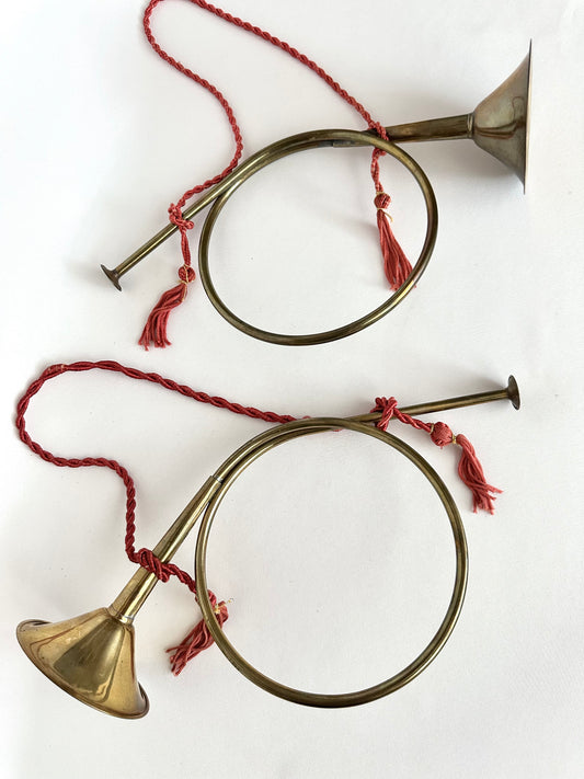 Vintage brass French horn set of two on braided red rope tassels.