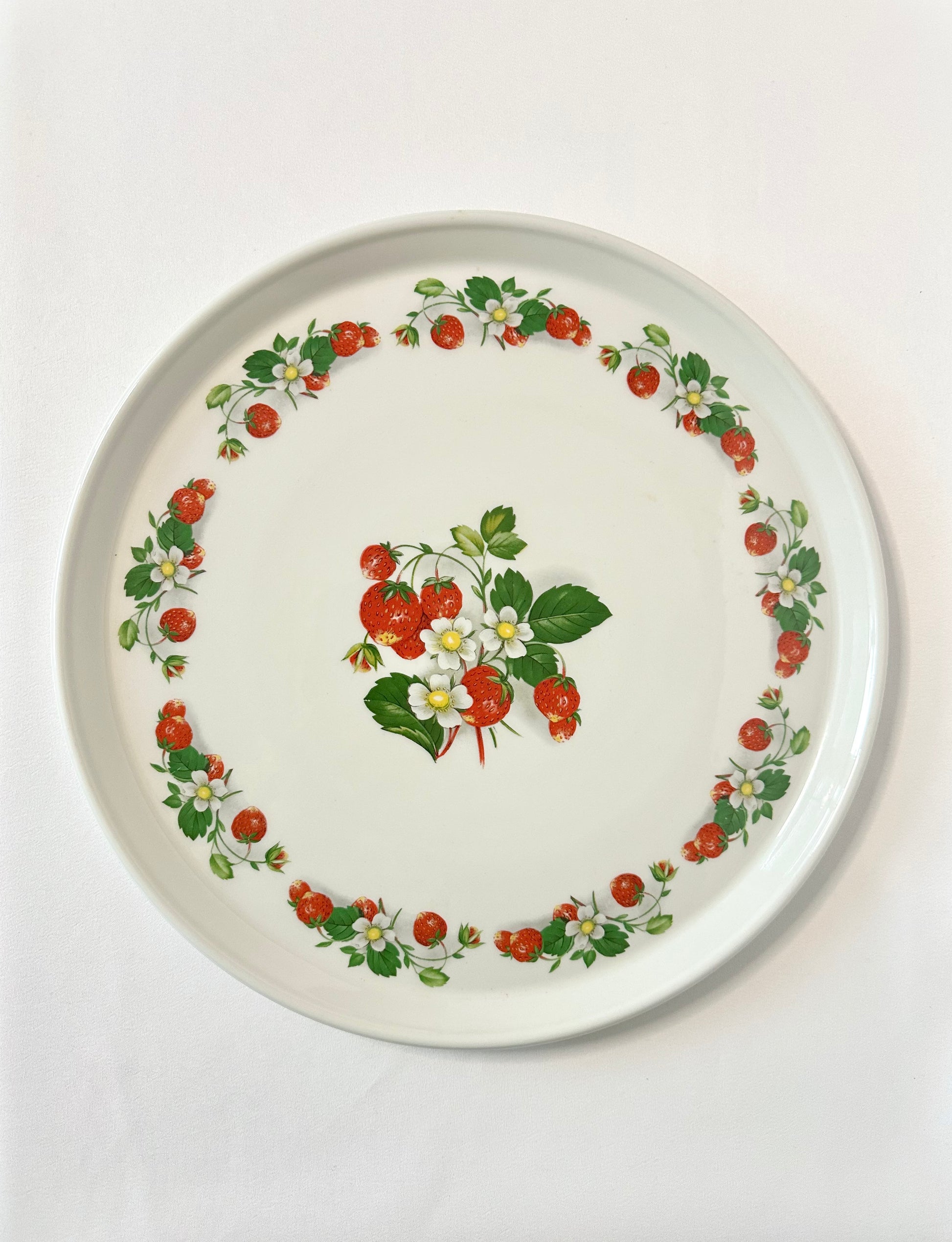 Vintage round ceramic serving platter featuring strawberries and white flowers. 