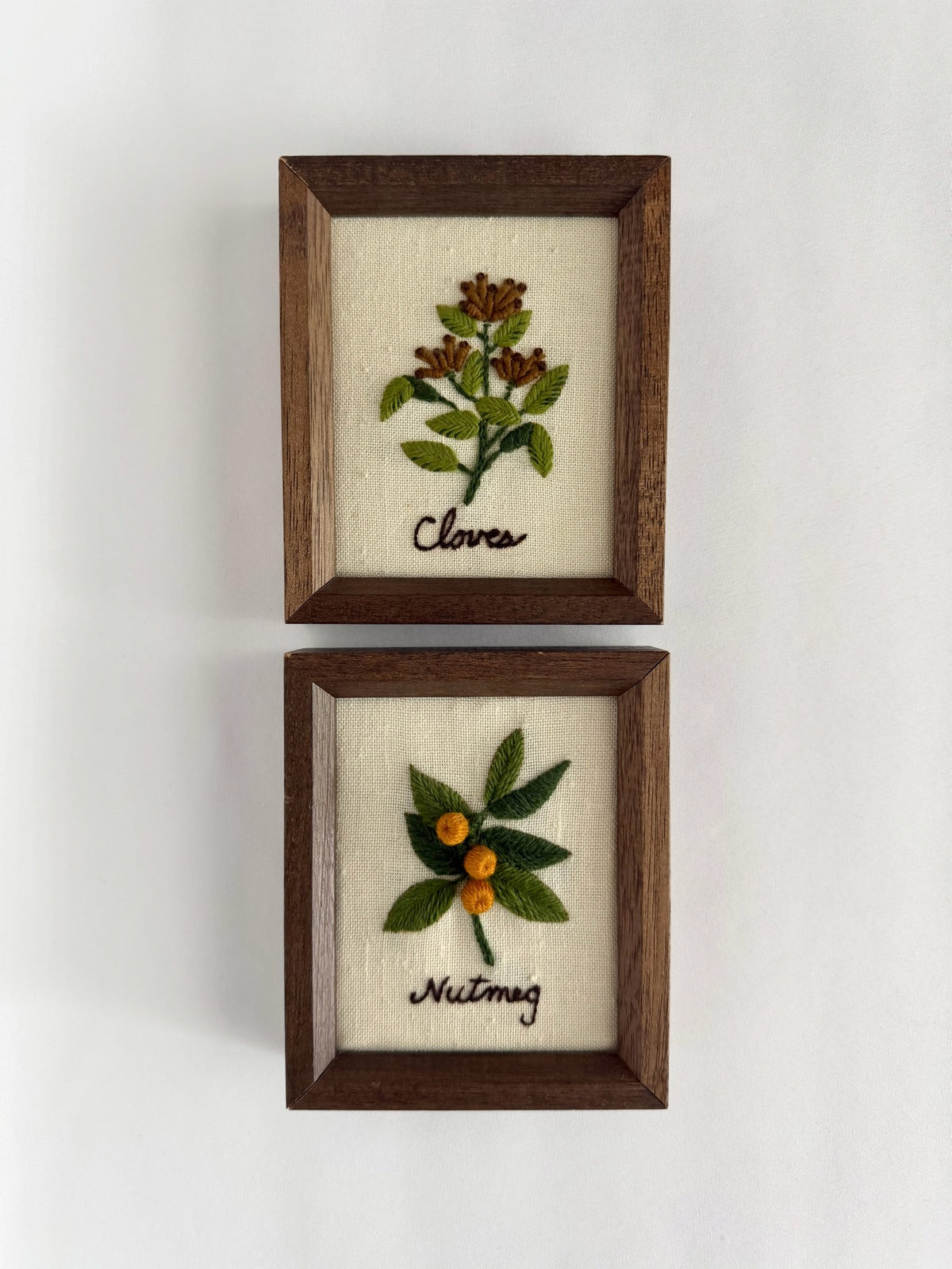 Vintage pair of small wood framed needlepoint art work featuring cloves and nutmeg.