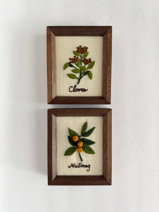 Vintage pair of small wood framed needlepoint art work featuring cloves and nutmeg.