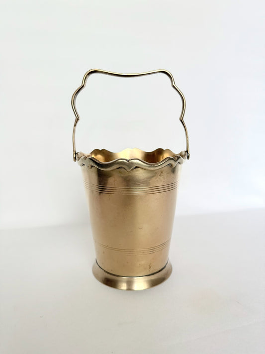 A small vintage brass ice bucket with a scalloped rim and a curved top handle, 