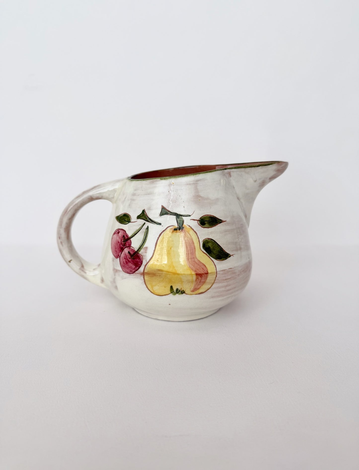 small vintage glazed ceramic pitcher with fruit detail in off white and brown interior